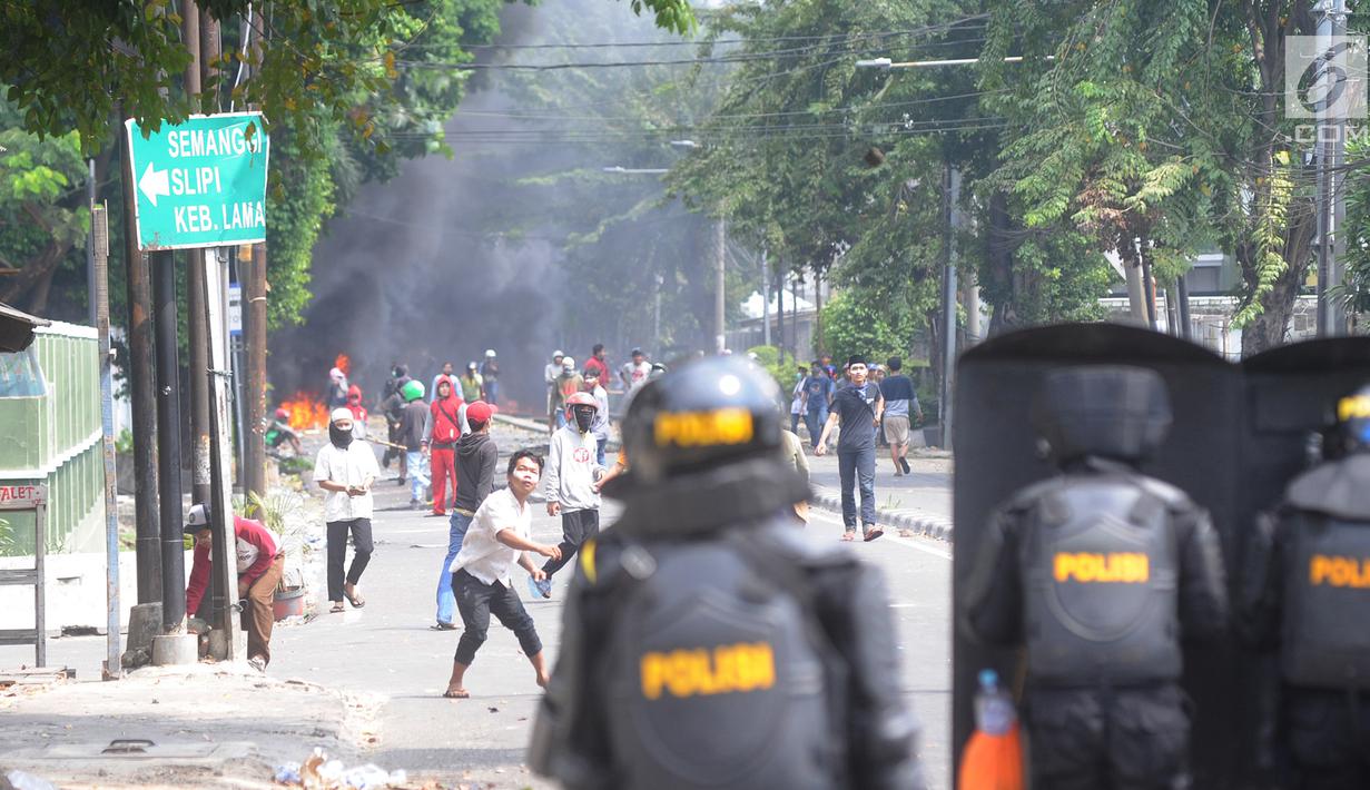 Pengunjuk rasa melemparkan batu ke arah petugas polisi selama bentrokan sebelum terjadi pembakaran bis milik Brimob di kawasan Tanah Abang,  Jakarta, Rabu (22/5/2019). (merdeka.com/Arie Basuki)