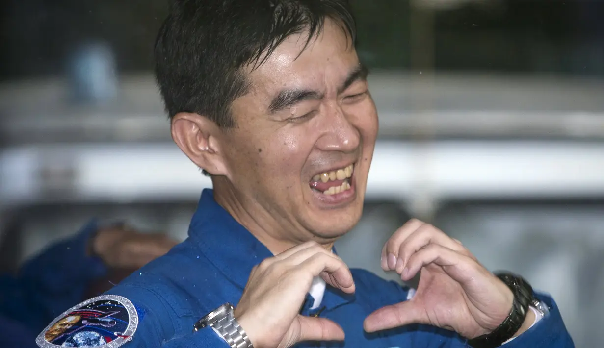 Kimiya Yui, seorang astronot asal Jepang memberikan gerakan isyarat dari dalam bus untuk keluarganya, sebelum keberangkatan ke luar angkasa di kosmodrom Baikonur, Kazakhstan, 22 Juli 2015. (REUTERS/Shamil Zhumatov)