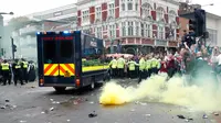 Petugas kepolisian menembakan bom asap saat suporter West Ham United menyerang bus skuat Manchester United di Upton Park,  London, Selasa (10/5). Kedatangan bus MU disambut dengan lemparan botol dari suporter fans West Ham. (Reuters/Eddie Keogh)