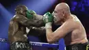 Petinju Inggris Tyson Fury melancarkan pukulan ke arah wajah petinju AS Deontay Wilder pada pertandingan tinju kelas berat WBC di Las Vegas (23/2/2020). Tyson Fury berhasil memenangkan pertarungan di ronde ketujuh. (AP Photo/Isaac Brekken)