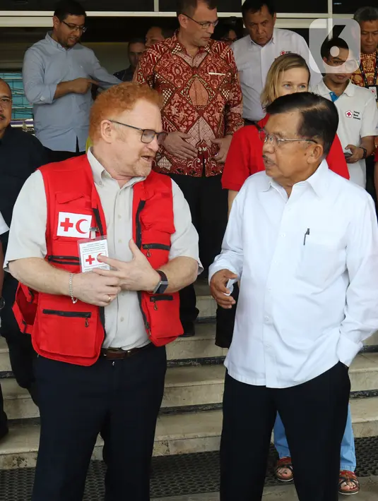 Ketua Umum Palang Merah Indonesia, Jusuf Kalla berbincang dengan Kepala IFRC Perwakilan Indonesia-Timor Leste dan ASEAN, Jan Gelfand, saat penyerahan secara simbolis bantuan 10 unit truk tangki air dan satu truk barang di Markas PMI Pusat, Jakarta, Jumat (17/1/2020). (Liputan6.com/Herman Zakharia)
