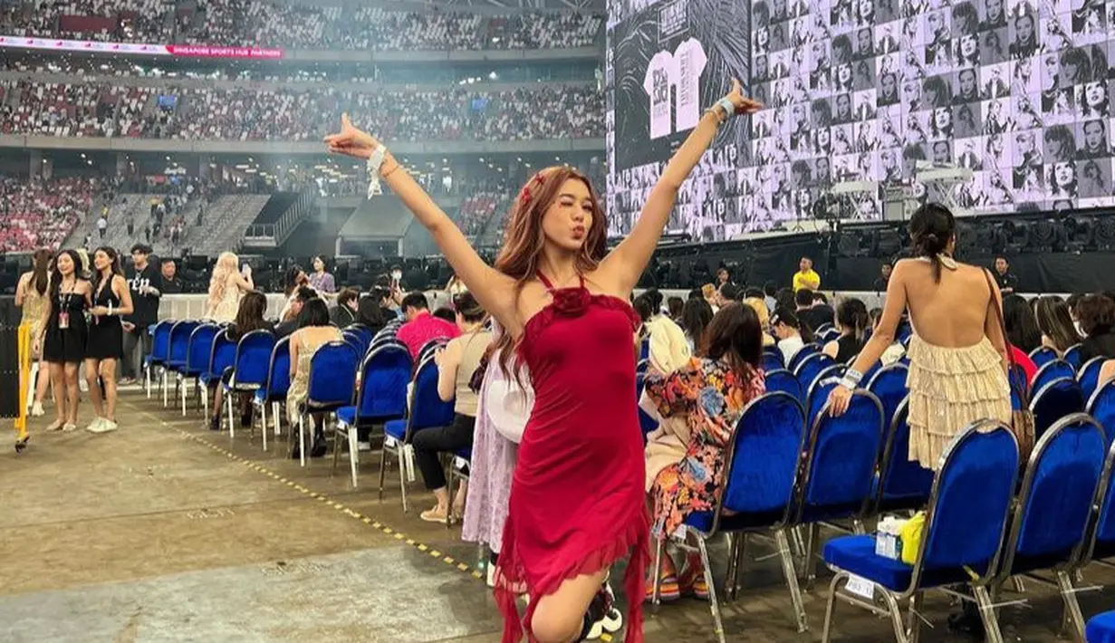 Gabriella Ekaputri tampil mengenakan dress merah dengan rumbai dan halterneck dihiasi bunga mawar di bagian dada. Dipadukan kaos kaki panjang bolong-bolong dan sepatu heels maroon. [@gabriellaekaputri]