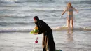 Seorang wanita muslim bermain di Pantai Laut Mediterania, Tel Aviv, Israel pada 22 Agustus 2016. Saat pengunjung pantai mengenakan busana yang minim mereka tetap mengenakan jilbab dan busananya. (REUTERS / Baz Ratner)