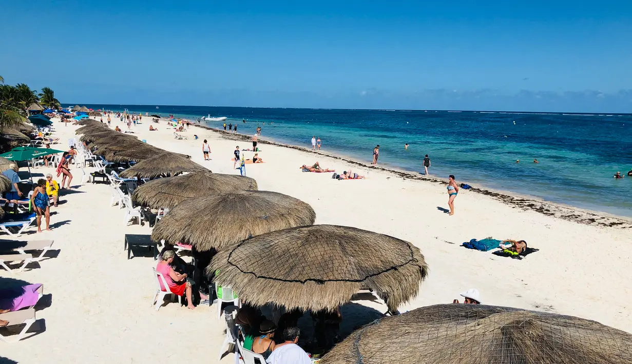 Wisatawan menikmati pantai di Puerto Morelos, negara bagian Quintana Roo, Meksiko (14/2). Kota ini terletak di timur laut negara bagian, sekitar 36 km selatan kota resor Cancún, dan sekitar 30 km utara kota Playa del Carmen. (AFP Photo/Daniel Slim)