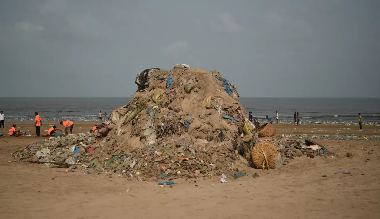 Petugas kebersihan berada di samping tumpukan sampah plastik terlihat di pantai Juhu di Mumbai, India (2/6). (AFP PHoto/Punit Paranjpe)