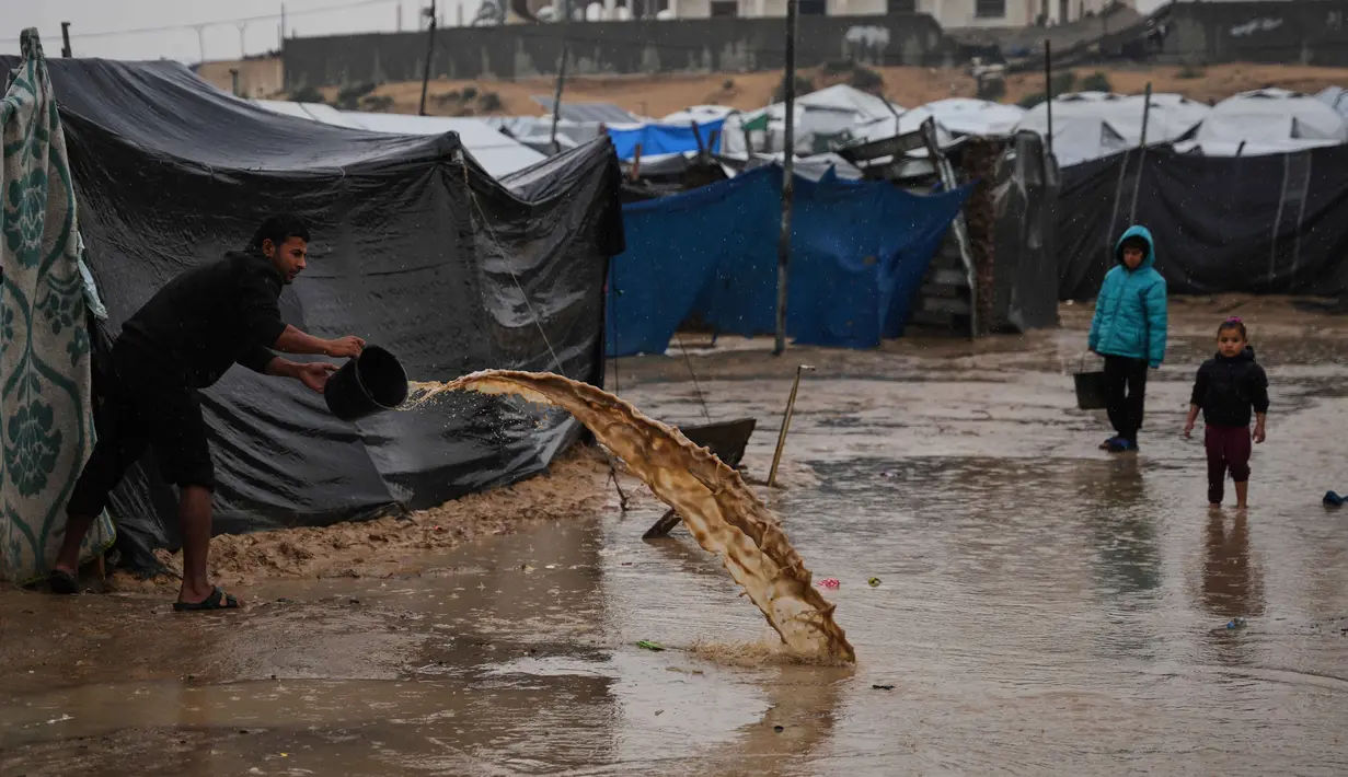 Kurangnya saluran drainase yang memadai dan kerusakan infrastruktur akibat perang yang berlangsung sejak Oktober 2023, membuat air sulit surut. Tampak dalam foto, seorang pria membersihkan air dari tendanya di sebuah kamp pengungsi Palestina setelah hujan deras di Deir al-Balah, Jalur Gaza, Kamis 11 Desember 2025. (AP Photo/Abdel Kareem Hana)