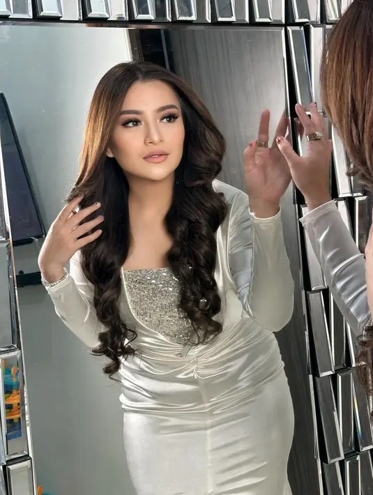 Rambut panjang kecoklatannya dibiarkan terurai dengan gaya belah dua. Pada bagian bawah rambut dibuat sedikit keriting.  [@nathalieholscher]