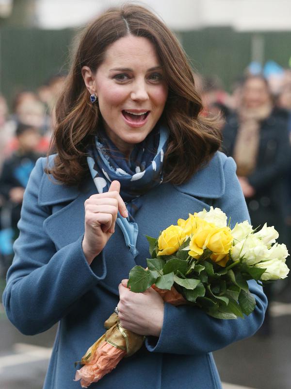 Kate Middleton tersenyum semringah usai menerima hadiah bunga dari anak-anak saat mengunjungi Roe Green Junior School di London, Inggris, Selasa (23/1). Kunjungan sekaligus peluncuran program kesehatan mental untuk anak-anak. (Jonathan Brady/POOL /AFP)