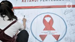 Warga membubuhkan tanda tangan saat berpartisipasi dalam peringatan Hari AIDS Sedunia di Bundaran HI, Jakarta, Minggu (1/12/2019). Kegiatan ini bertujuan mengedukasi masyarakat tentang penyakit AIDS dan mengajak untuk peduli serta tidak menjauhkan penderita AIDS. (merdeka.com/Iqbal S. Nugroho)