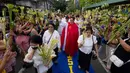 Seorang pemuka agama Katolik memberkati umat yang memegang daun palem di sepanjang jalan selama prosesi untuk menandai Minggu Palma sebagai bagian dari devosi jelang perayaan Paskah di Manila, Filipina pada 13 April 2025. (Ted ALJIBE/AFP)