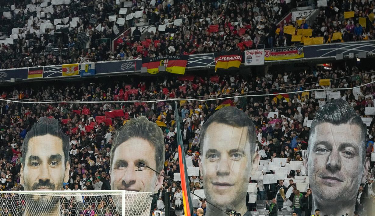 Saat pertandingan baru dimulai, penggemar Timnas Jerman menampilkan koreo di tribune belakang gawang. Penggemar menggunakan momen ini untuk memberikan penghormatan kepada empat pemain Timnas Jerman yang baru saja pensiun dari sepak bola internasional. (AP Photo/Matthias Schrader)