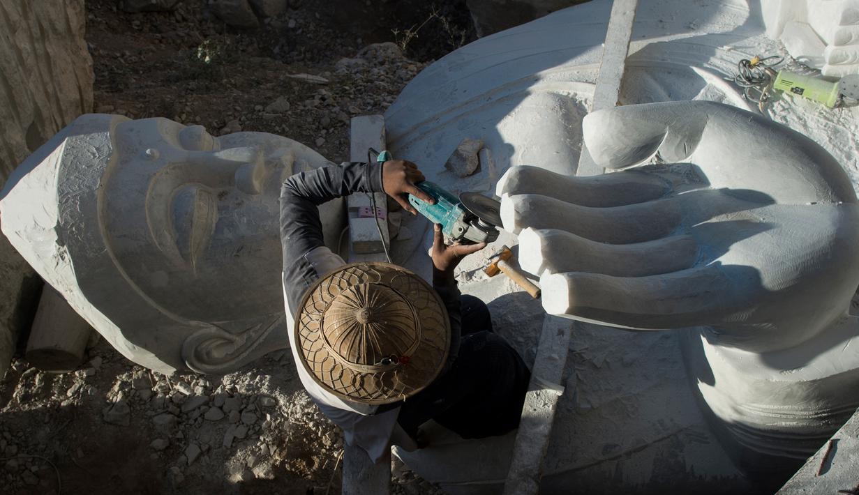 Seorang pekerja mengukir patung Buddha yang terbuat dari batu marmer di desa Sagyin, Madaya, Myanmar pada 22 Desember 2018.  Patung-patung marmer yang diproduksi di desa Sagyin ini diekspor ke Thailand, Vietnam, dan Taiwan. (YE AUNG THU / AFP)