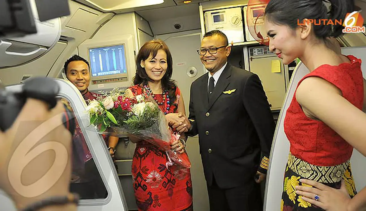 Kapten Pilot Citilink mempersembahkan rangkain bunga untuk Ika Puspitarini sebagai tanda berakhirnya fashion show di udara, yang untuk pertama kalinya digelar di Indonesia. (Liputan6.com/Danu Baharuddin)