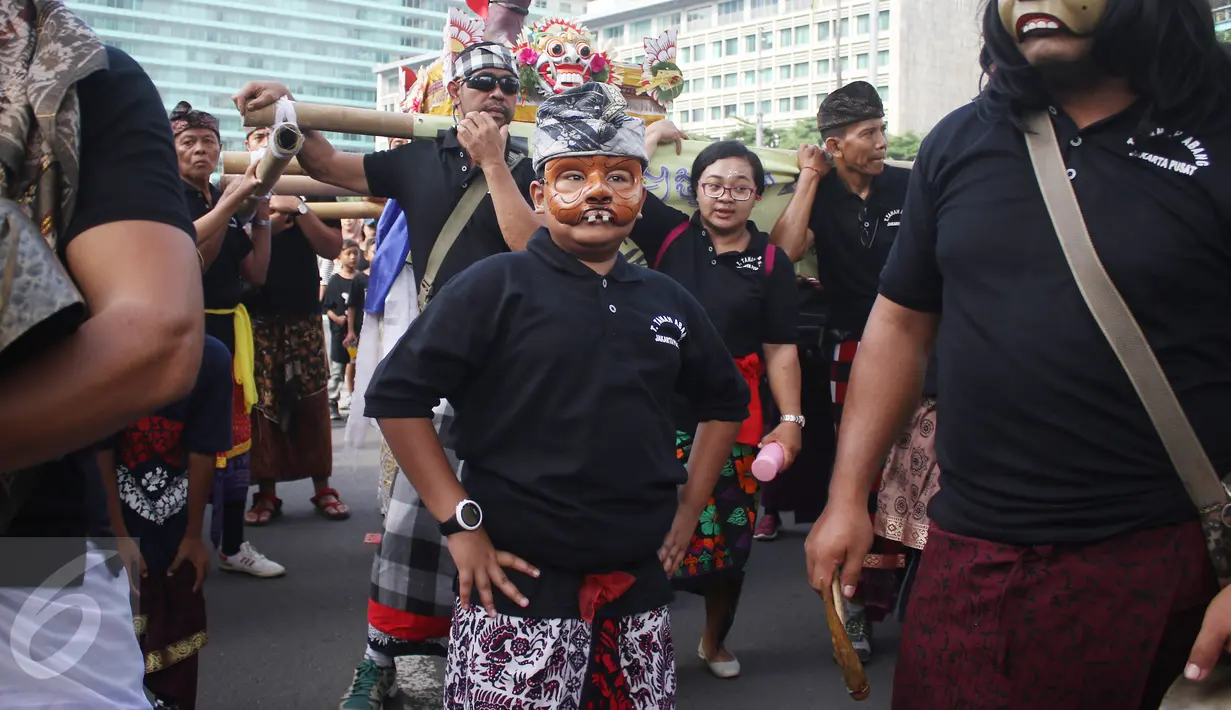 Seorang anak mengenakan topeng saat sosialisasi pawai ogoh-ogoh di kawasan CFD, Bundaran HI, Jakarta, Minggu (19/3). Pawai ogoh-ogoh akan diadakan secara besar di Pura Agung Wira Satya Bhuana, Jakarta, pada Senin (27/3). (Liputan6.com/Angga Yuniar)