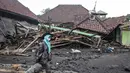 Seorang perempuan melintas di depan sebuah rumah yang hancur akibat aliran piroklastik Gunung Semeru di Desa Supiturang, Lumajang, Jawa Timur, pada Jumat 21 November 2025. Hari ketiga pasca-erupsi Gunung Semeru, atau Jumat (21/11/2025), Pemerintah Desa Supiturang, Kecamatan Pronojiwo, Kabupaten Lumajang, Jawa Timur, mencatat sedikitnya lebih dari 200 rumah dan fasilitas umum rusak parah. (Agus Harianto/AFP)