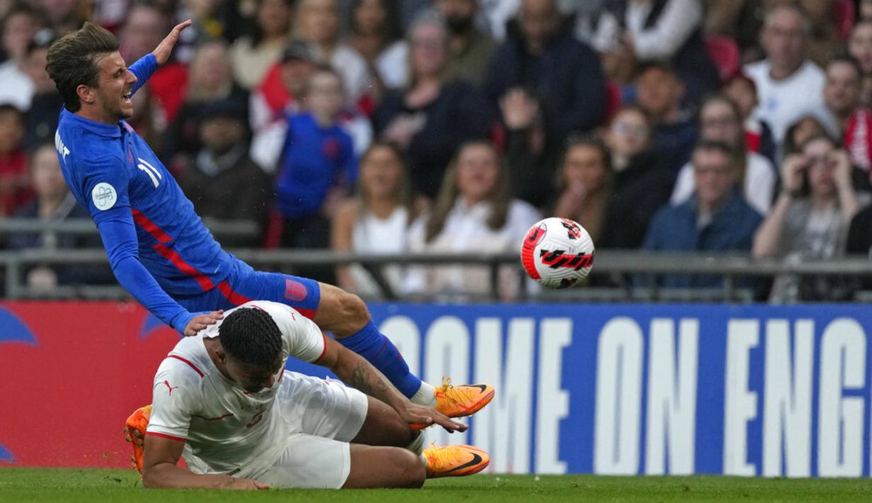 Pemainn Inggris Mason Mount (atas) berebut bola dengan pemain Swiss Manuel Akanji pada pertandingan uji coba di Stadion Wembley, London, Inggris, 26 Maret 2022. Inggris menang 2-1. (AP Photo/Alastair Grant)