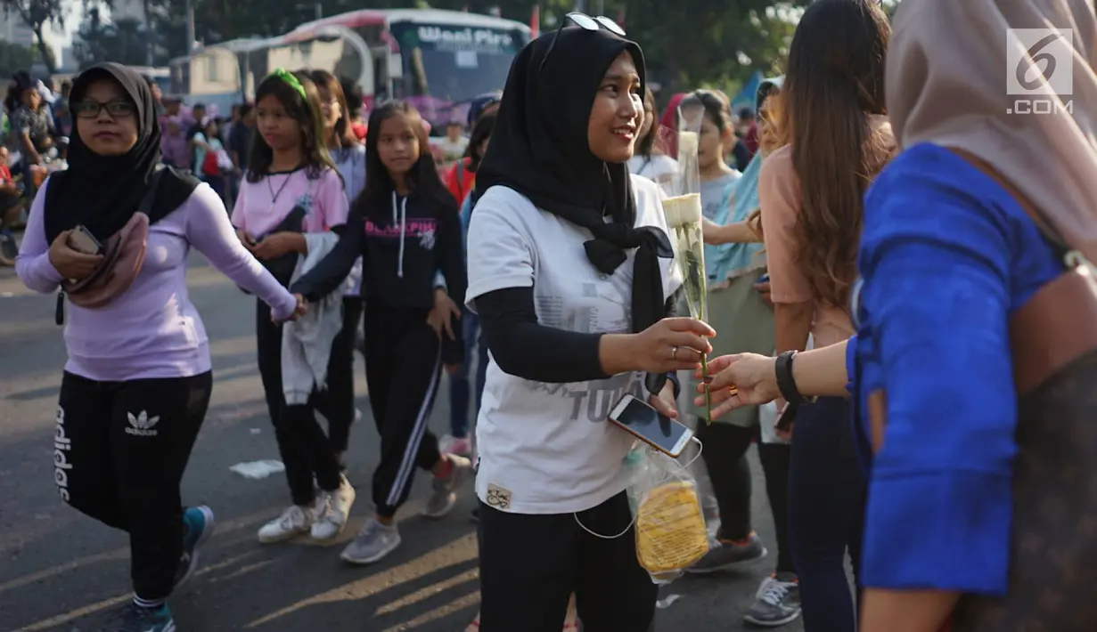 Sejumlah relawan membagikan bunga mawar ke warga saat berlangsungnya kegiatan car free day di kawasan Bundaran HI, Jakarta, Minggu (30/6/2019).  Aksi 1000 bunga mawar itu sebagai bentuk rasa syukur atas kemenangan pasangan Jokowi-Ma'ruf Amin di Pilpres 2019. (Liputan6.com/Immanuel Antonius)