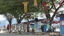 Seorang pria membawa kursi melewati pohon yang berhias barang-barang untuk memperingati gempa dan tsunami Palu, Rabu (3/4). Kondisi Palu mulai membaik setelah bencana gempa dan tsunami melanda melanda enam bulan lalu. (OLAGONDRONK/AFP)