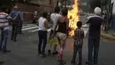 Patung yang dipasang gambar Presiden Venezuela Nicolas Maduro dibakar oleh warga di Caracas , Venezuela, (27/3). Hal ini dilakukan dalam perayaan Paskah di Caracas. (REUTERS / Marco Bello)
