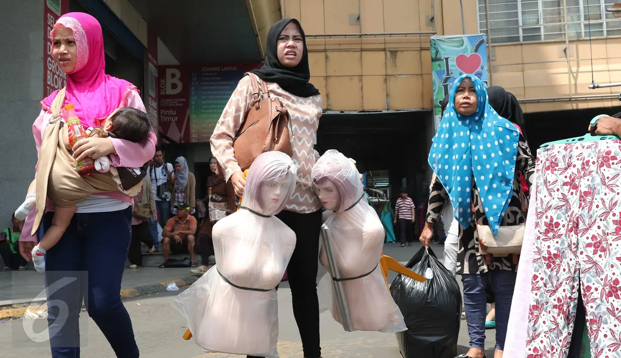 Sejumlah pembeli membawa barang belanjaan mereka di Pasar Tanah Abang, Jakarta, Rabu (9/12). Libur pilkada dimanfaatkan warga untuk berbelanja pakaian di pasar tekstil terbesar di Asia Tenggara itu. (Liputan6.com/Angga Yuniar)