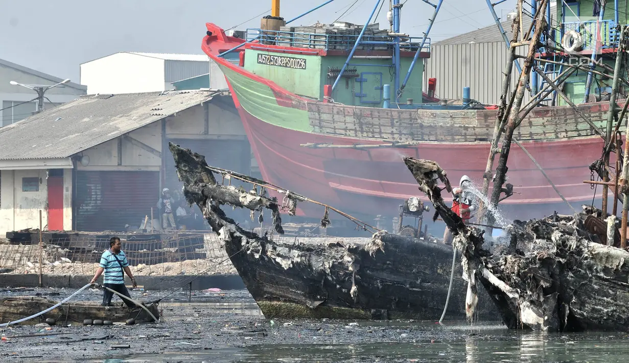 Sejumlah pria melakukan pendinginan kapal yang ludes dilalap api di Pelabuhan Muara Baru, Jakarta, Minggu (24/2). Sebanyak 23 unit kendaraan pemadam dikerahkan untuk memadamkan api saat kebakaran. (Merdeka.com/Iqbal Nugroho)