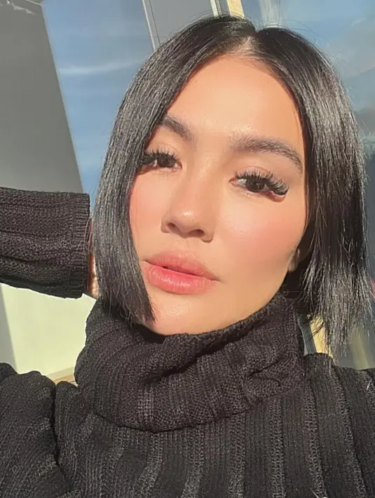 Ia juga tampil dengan turtle neck hitam knit, dengan riasan wajah yang natural. [@agnezmo]