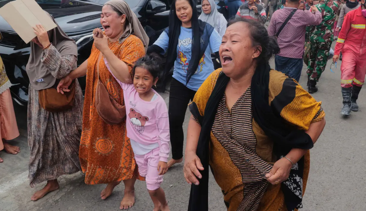 Diduga masih terdapat 38 orang yang masih terjebak dalam reruntuhan. Tampak dalam foto, beberapa perempuan bereaksi saat mereka menjauh setelah bangunan runtuh di sebuah pesantren di Sidoarjo, Jawa Timur, Selasa 30 September 2025. (AP Photo/Trisnadi)