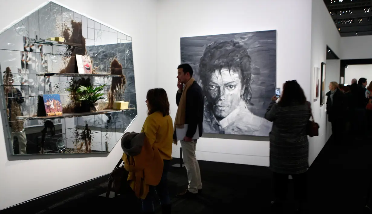 Pengunjung melihat lukisan seniman AS Rashid Johnson "The Whiz" (2012) dan "In Memory of Michael Jackson" (2017) karya seniman China Yan Pei-Ming dalam pameran Michael Jackson: On The Wall di museum Grand Palais, Paris, Rabu (21/11). (AP/Francois Mori)