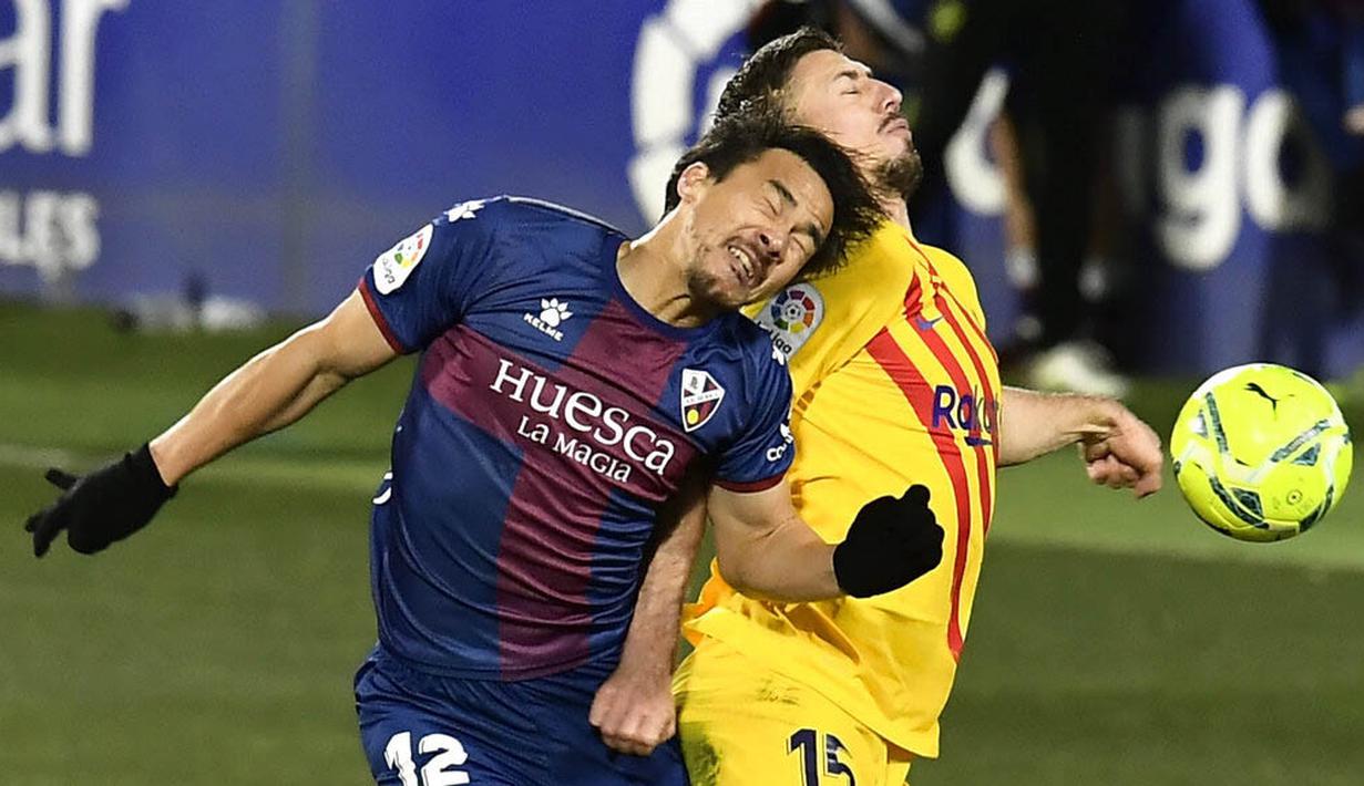Pemain Barcelona, Clement Lenglet, duel udara dengan pemain Huesca, Shinji Okazaki, pada laga Liga Spanyol di Stadion El Alcoraz, Minggu (3/1/2021). Barcelona menang tipis dengan skor 1-0. (AP/Alvaro Barrientos)