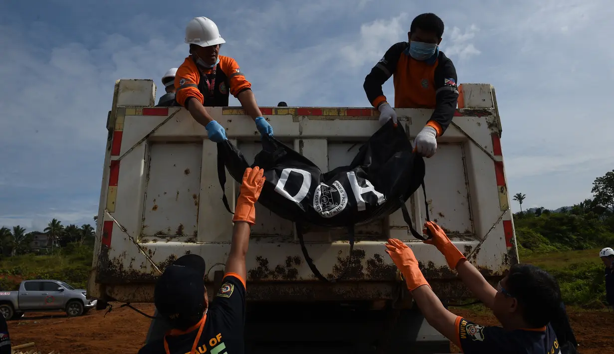 Petugas menurunkan jenazah korban pengepungan Marawi saat pemakaman massal di sebuah pemakaman umum di Marawi, di pulau selatan Mindanao (24/7). Perang di Marawi memasuki bulan kedua. (AFP Photo/Ted Aljibe)