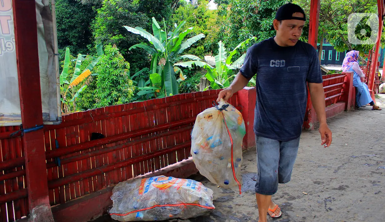 Warga membawa karung berisi sampah yang diangkuta dari Kali Baru di Jalan Pitara Raya, Depok, Jawa Barat, Rabu (19/2/2020). Warga kerja bakti mengangkut sampah dari kali agar aliran sungai tetap lancar. (merdeka.com/Magang/Muhammad Fayyadh)