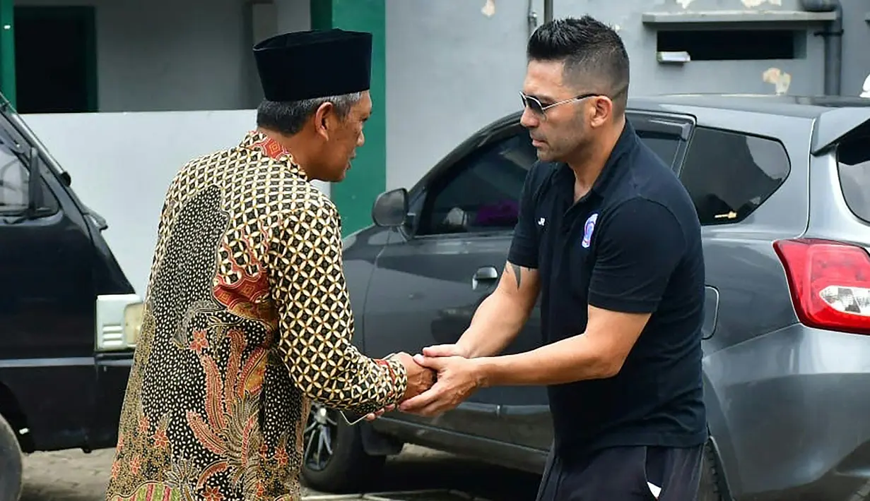 Pelatih Arema FC, Javier Roca menyalami kerabat salah seorang korban Tragedi Kanjuruhan yang merupakan putra pengasuh Pondok Pesantren Miftahul Ulum Atthohirin, Gondanglegi, Malang. (AFP/Putri)