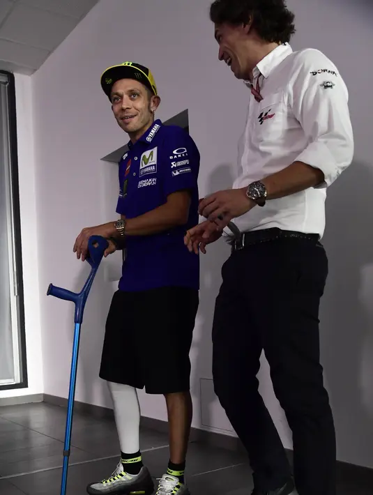 Pebalap Movistar Yamaha, Valentino Rossi, menggunakan tongkat menghadiri jumpa pers jelang GP Aragon di Alcaniz, Aragon, Kamis (21/9/2017). Rossi dinyatakan lolos tes medis untuk mengikuti balapan MotoGP Aragon. (AFP/Javier Soriano)