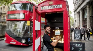 Seorang pria bernama Fouad Choaibi bekerja mereparasi ponsel didalam kotak telepon merah di Southhampton Row, London (20/10). Menjamurnya ponsel, membuat telepon umum di Inggris ini tidak beroperasi lagi. (AFP Photo/Tolga Akmen)