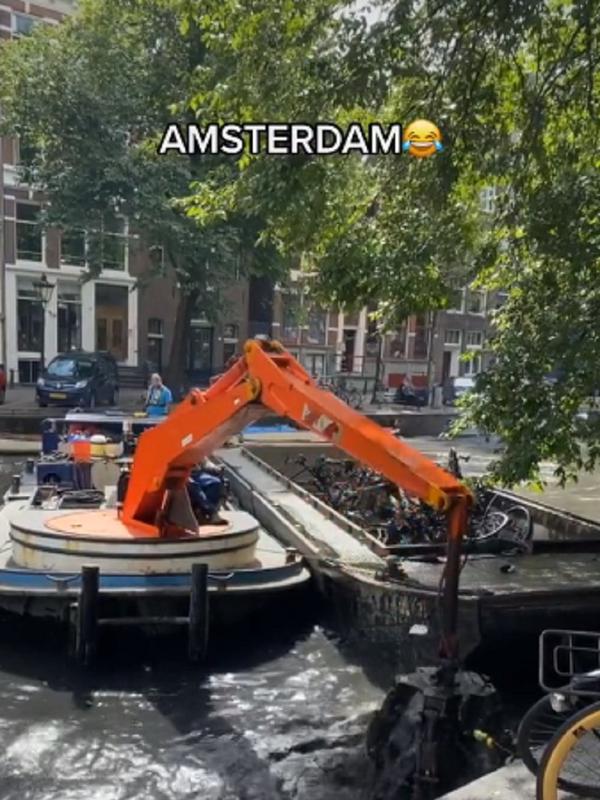 Petugas mengangkut bangkai sepeda di kanal sungai Amsterdam.