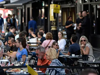 Pelanggan menikmati makan siang di meja di luar restoran di Soho, London, ketika pemerintah Inggris mempertimbangkan pembatasan baru pada Minggu (20/9/2020). Inggris kemungkinan akan kembali memberlakukan tindakan lockdown akibat lonjakan tajam infeksi virus corona COVID-19. (DANIEL LEAL-OLIVAS/AFP)