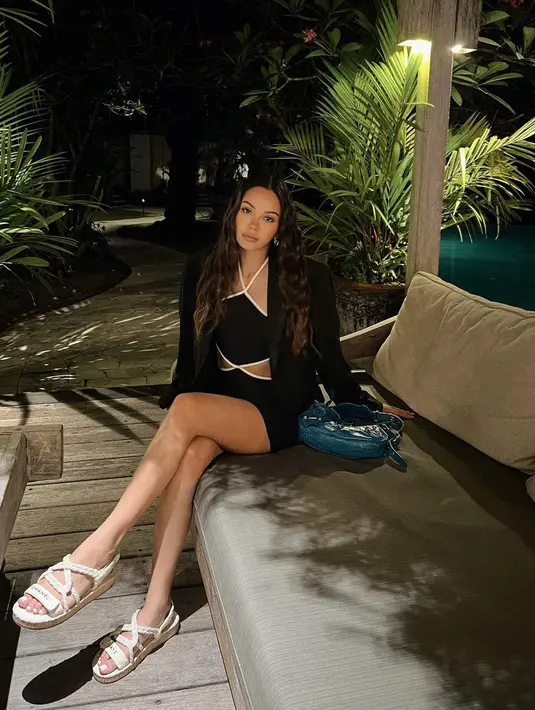 Menikmati Bali di malam hari, Alyssa Daguise mengenakan halter strap dress berwarna hitam dengan outline putih. Dress dengan cutout di bagian pinggang itu dipadukan dengan blazer berwarna hitam dan tas Balenciaga Le Cagole berwarna biru. (instagram/alyssadaguise)
