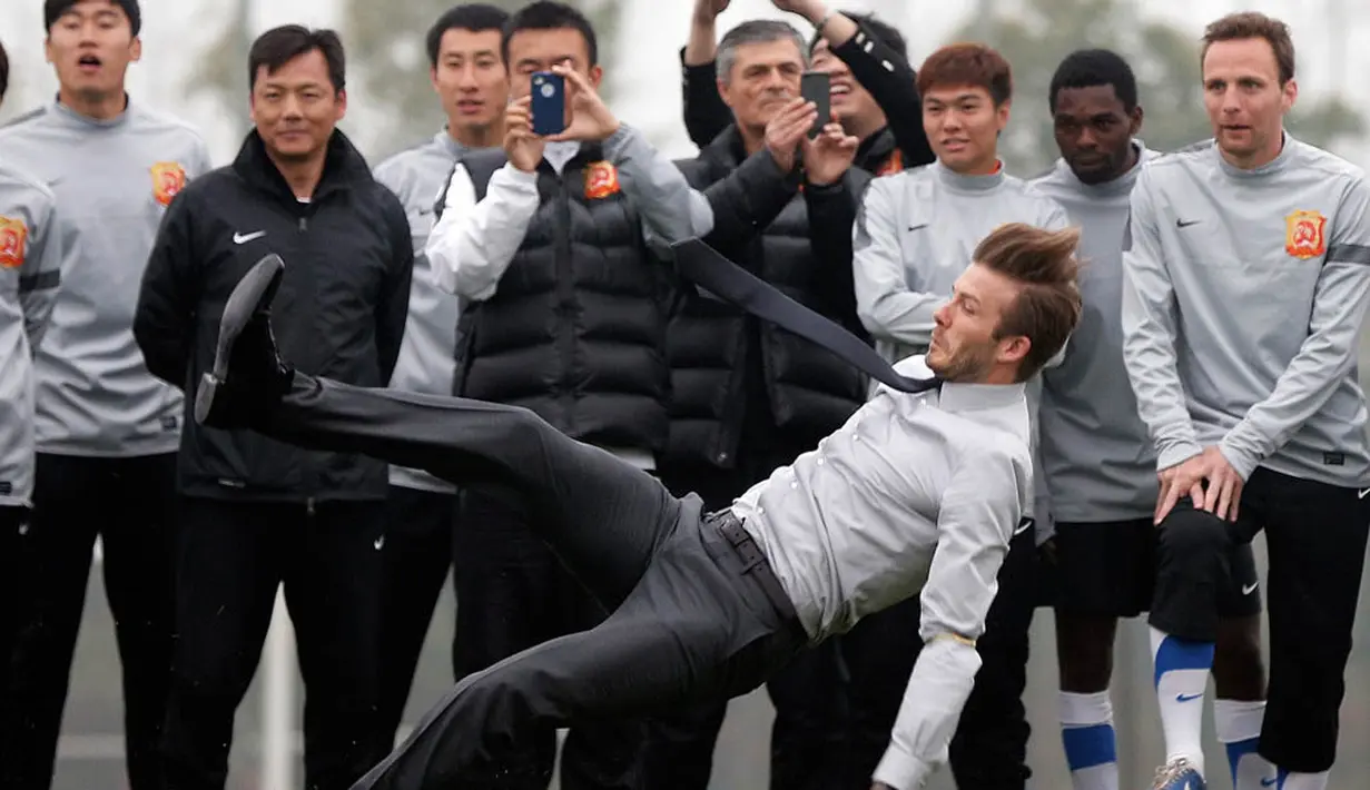 Atlet tampan David Beckham terjatuh usai memperagakan aksi menendang bola di Cina. (Lintao Zhang/Getty Images)