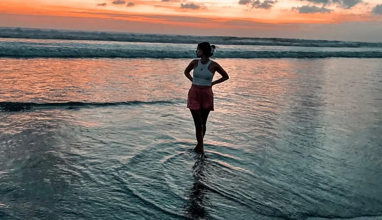 Suka traveling ke alam mulai dari pantai hingga air terjun, Ria Andrews percaya diri dengan warna kulit eksotis. Kini menetap di Bali, Ria Andrews memang sering bagikan foto keindahan Pulau Dewata, Bali. Seperti salah satunya saat ia liburan di pantai sembari melihat keindahan sunset di langit Bali ini yang diunggah di laman Instagram pribadinya pada tahun 2021. (Liputan6.com/IG/ria.travelwithmeri)