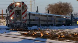 Sebuah kereta komuter melaju menuju pusat kota Chicago ketika api menyala di sepanjang rel di dekat stasiun Metra Western Avenue, 29 Januari 2019. Metra memakai sistem pemanas berbahan bakar gas untuk menghangatkan lintasan yang dingin. (AP/Kiichiro Sato)