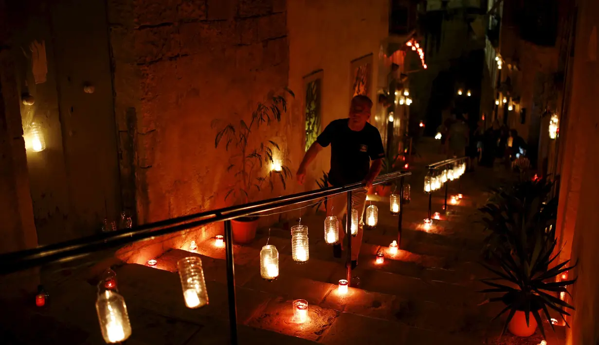 Seorang pria menaiki tangga yang telah dihiasi oleh puluhan lilin saat digelarnya festival Birgu di Malta, Sabtu (10/10/2015). Acara ini berlangsung dari 9 - 11 oktober 2015. (REUTERS/Darrin Zammit)