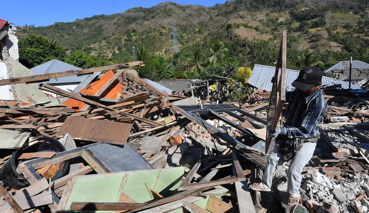 Seorang pria menyelamatkan sisa-sisa puing dari bangunan rumah yang rusak di Menggala, Lombok Utara, Rabu (8/8). Warga terdampak gempa Lombok mulai mengamankan barang berharga miliknya karena kuatir dijarah pihak tidak bertanggung jawab. (AFP/ADEK BERRY)