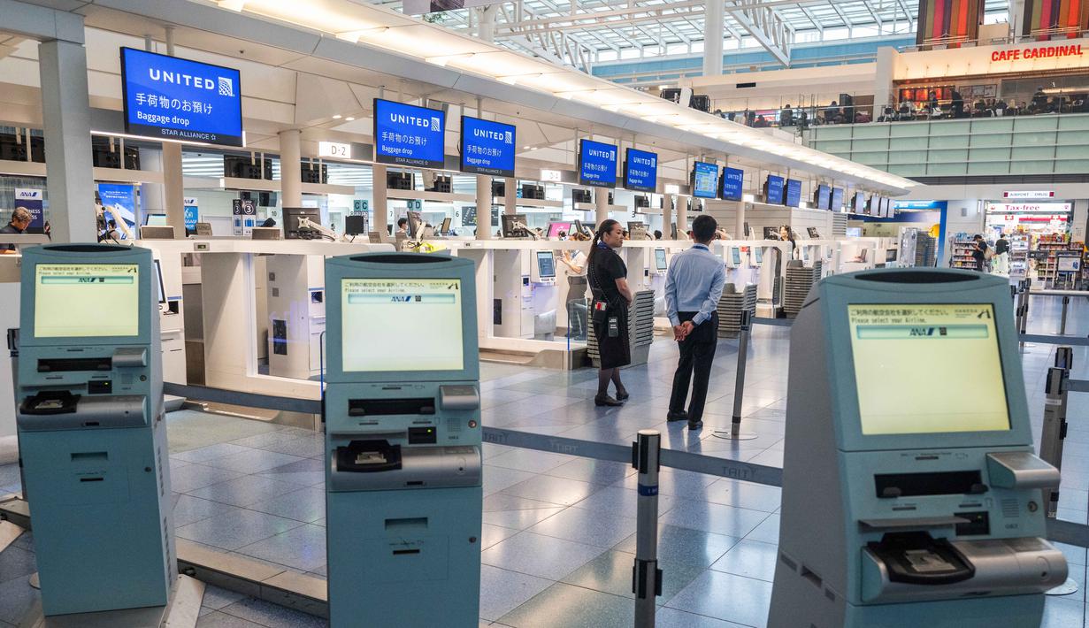 Staf maskapai penerbangan menunggu di konter check-in yang kosong di Terminal Internasional Bandara Haneda setelah penerbangan dibatalkan atau ditunda karena badai tropis Jangmi di Tokyo, Jepang, Rabu 3 Juni 2026. (Andrew CAALLERO-REYNOLDS/AFP)
