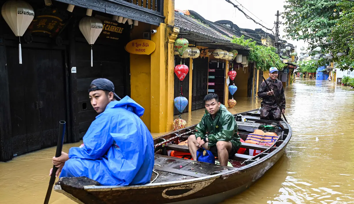 Orang-orang menyusuri jalan yang terendam banjir dengan perahu setelah hujan deras di Hoi An, Vietnam, Kamis 30 Oktober 2025. Badan Penanggulangan Bencana Nasional Vietnam mengatakan ada lebih dari 103.000 rumah terendam banjir, terutama di kawasan wisata utama Hue dan Hoi An. (NHAC NGUYEN/AFP)