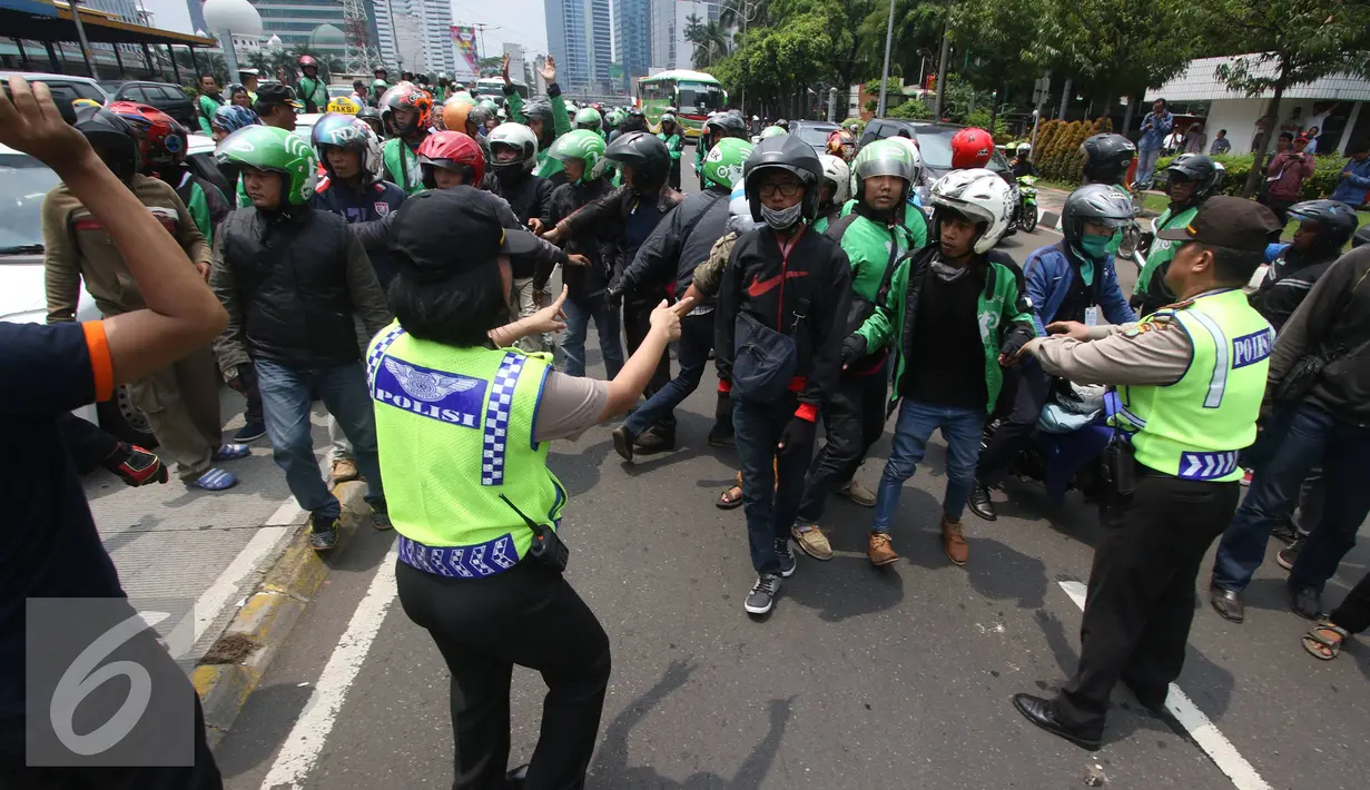 Petugas menenangkan pengadara Go-Jek yang terlibat kericuhan di Jakarta, Selasa (22/3). Ratusan Go-Jek mendatangi para sopir taksi karena tersebar isu pemukulan terhadap beberapa pengendara Go-Jek oleh sopir taksi.  (Liputan6.com/Immanuel Antonius)