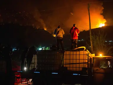 Orang-orang menunggu di atas truk air saat kebakaran hutan berkobar di Gunung Pirque, El Hoyo, wilayah Patagonia provinsi Chubut, Argentina pada 7 Januari 2026. Ribuan hektar hutan di Gunung Pirque, El Hoyo, wilayah Patagonia provinsi Chubut, Argentina, hancur akibat kebakaran yang terjadi sejak 6 Januari 2026. (Martin LEVICOY/AFP)