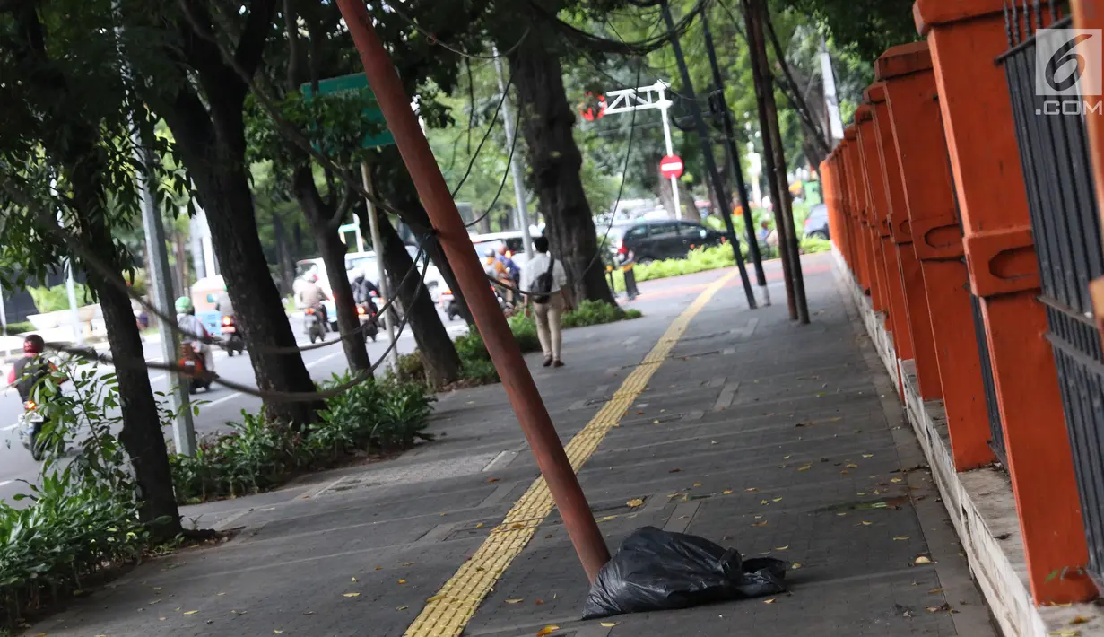 Kondisi tiang yang miring di Jalan Gedung Kesenian, Jakarta, Jumat (22/2). Keberadaan tiang miring tersebut membahayakan keselamatan pejalan kaki karena kabel yang turut menjuntai hingga ke bawah. (Liputan6.com/Immanuel Antonius)