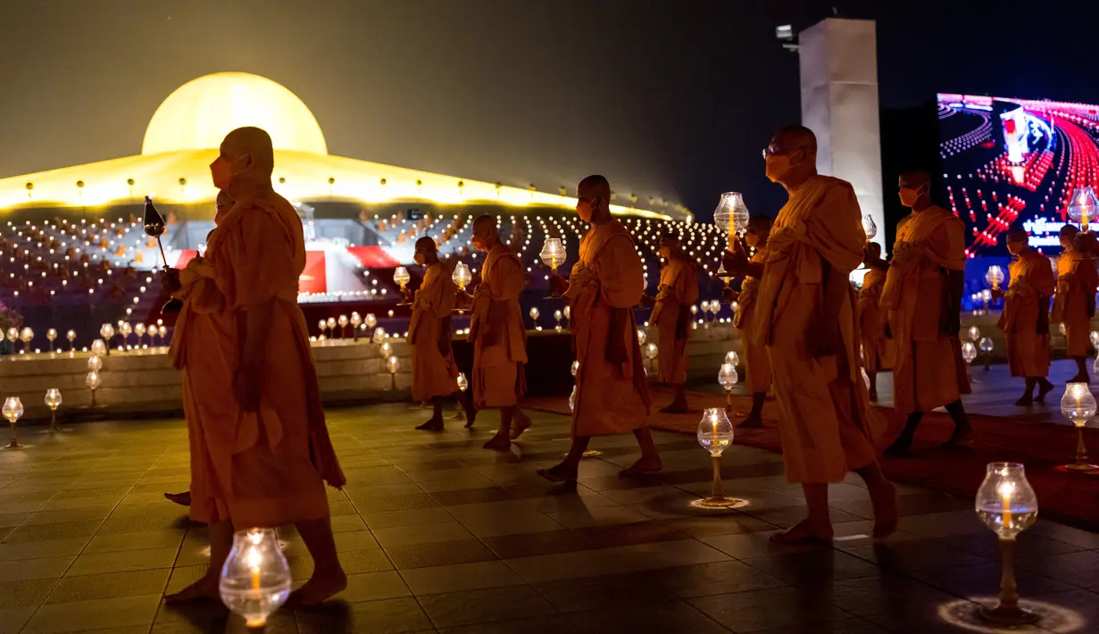 Biksu Buddha membawa lilin selama perayaan Makha Bucha di kuil Wat Dhammakaya di provinsi Pathum Thani, utara Bangkok (16/2/2022). Makha Bucha merupakan salah satu hari raya terpenting bagi para penganut agama Buddha. (AFP/Jack Taylor)