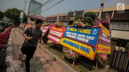 Warga melintasi karangan bunga di Halaman Polres Jakarta Barat, Jumat (23/11). Puluhan karangan bunga yang dikirimkan warga tersebut diberikan guna mendukung pihak kepolisian dalam memberantas aksi premanisme di Jakarta Barat. (Liputan6.com/Faizal Fanani)