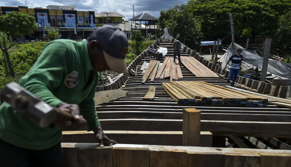 Pekerja menyelesaikan pembuatan kapal nelayan di Banda Aceh, Aceh pada 21 November 2020. Industri galangan kapal tradisional di daerah itu mengalami kesulitan memperoleh bahan baku kayu untuk memproduksi kapal nelayan, sehingga berdampak pada proses penyelesaian kapal. (CHAIDEER MAHYUDDIN/AFP)
